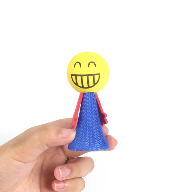 Hand holding a small figurine with a smiley face and blue body on a white background