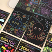 Scratch art cards with colorful designs on a wooden surface