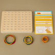 Educational tool with wooden board, colored rings, and flashcards on a beige background