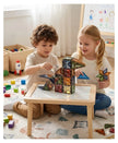 Two children playing with magnetic building toys on a table in a room with colorful toys scattered around.