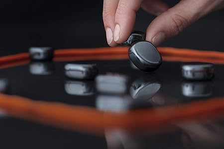 Hand placing a black object on a reflective surface with orange border