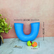 Blue letter 'U' toy with measurements and colorful balls on a marble surface.