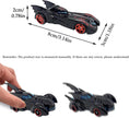 Toy Batmobile with measurements and a hand for scale on a white background